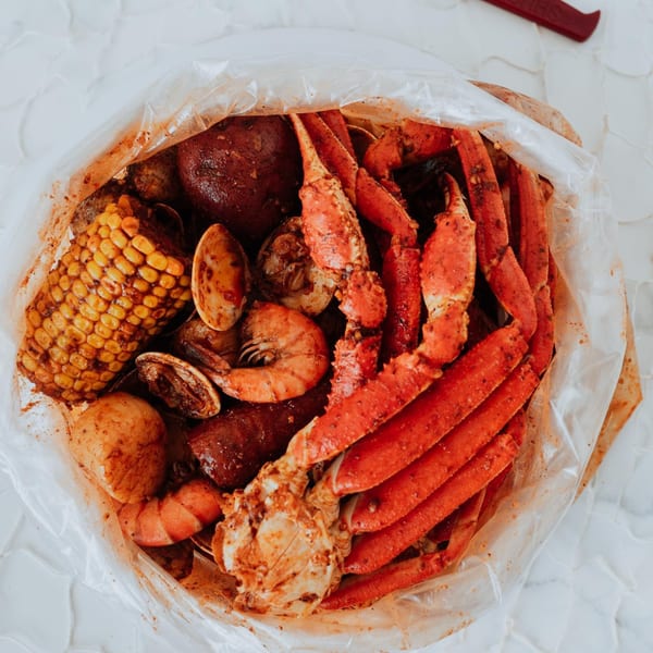 A seafood boil bag from Crackin' Crab, filled with crab legs, shrimp, corn, potatoes, and clams.